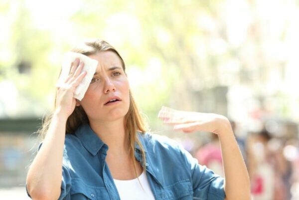 a woman wiping her forehead with a tissue