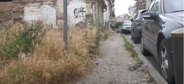 a dirt road with graffiti on the side of a building