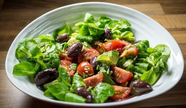 a bowl of salad with tomatoes olives and lettuce