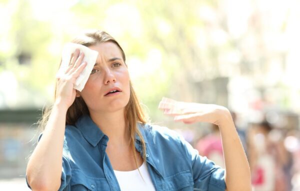 a woman wiping her forehead with a towel